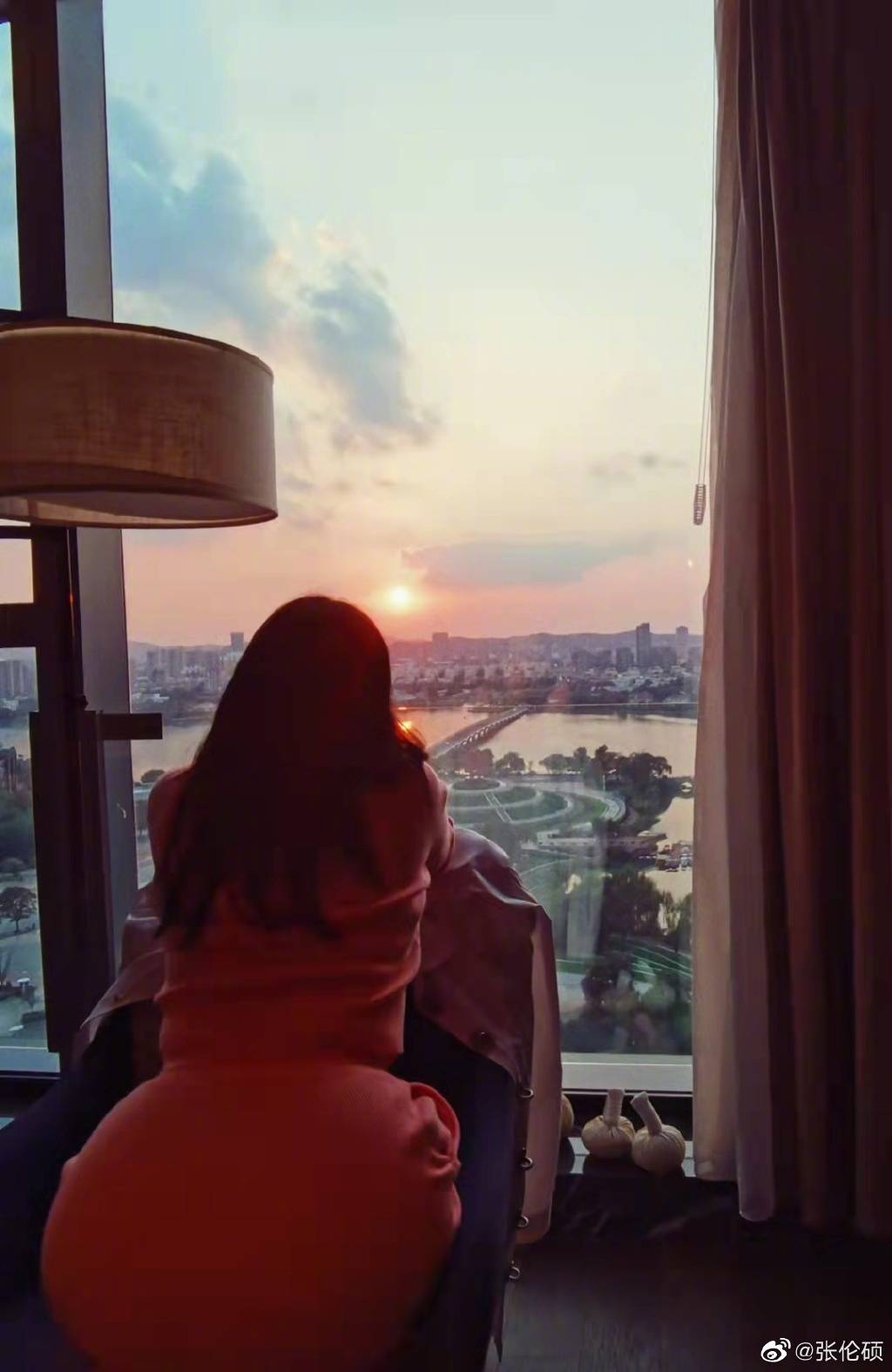 照片中,钟丽缇一个人趴在椅子望向窗外的夕阳,背影画面非常唯美.