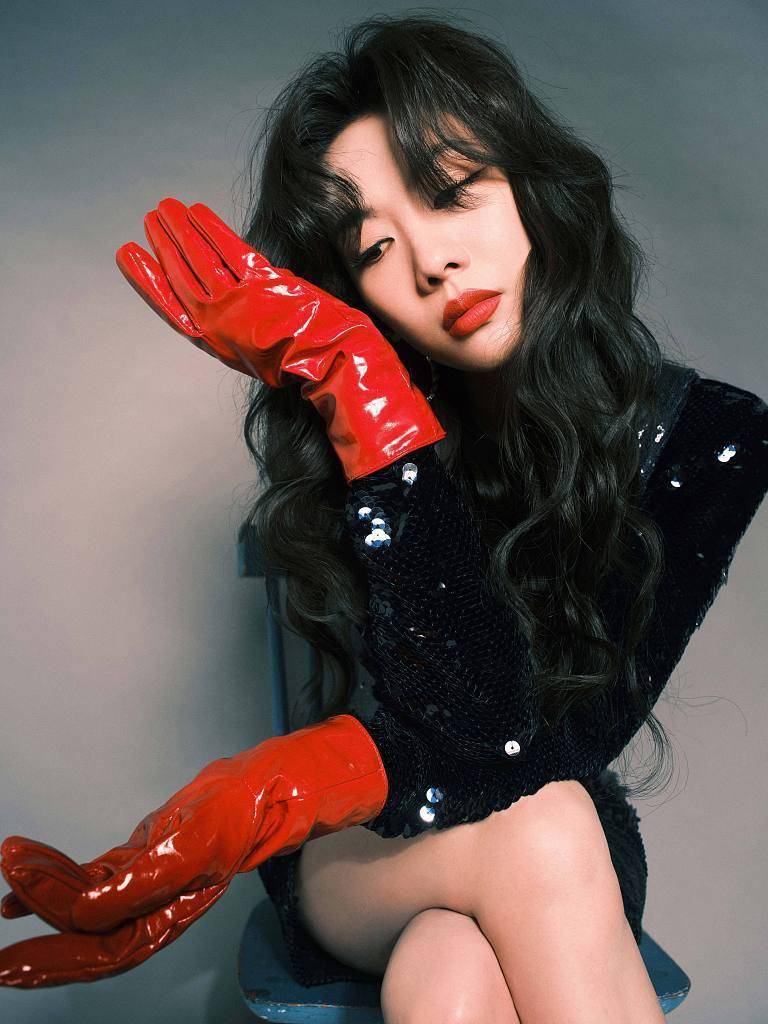 王霏霏出席芒果年货节复古波浪卷发搭配亮面红手套摩登感十足