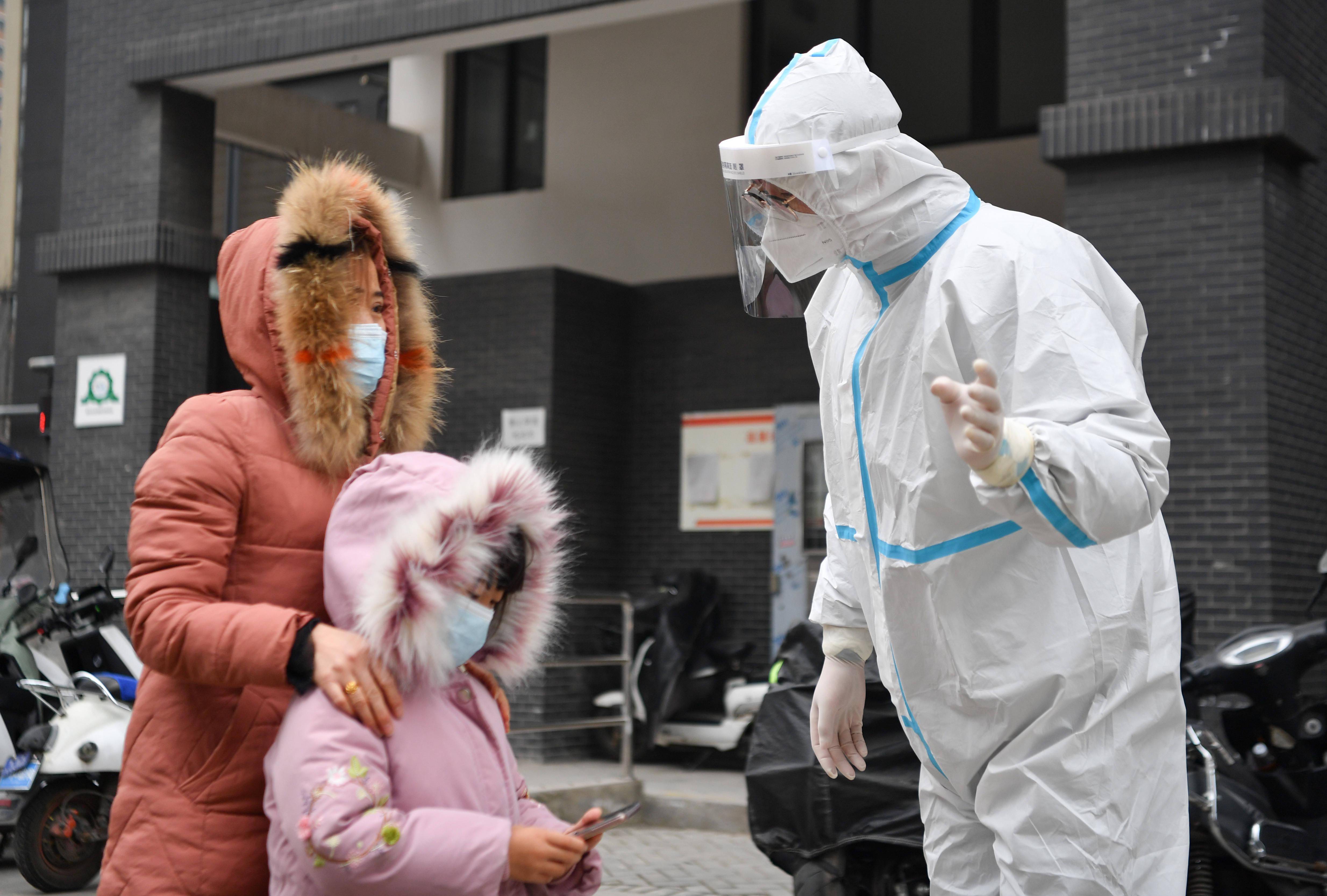 2021年12月27日,在西安市雁塔区孟村小区,工作人员向居民介绍核酸检测