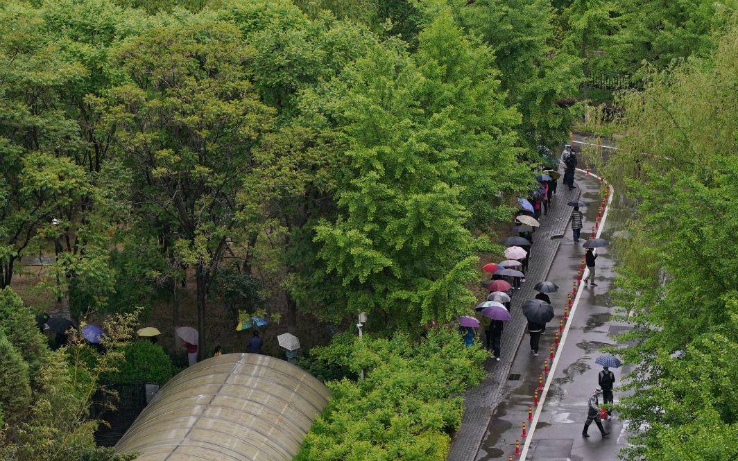 多图｜北京朝阳区临时管控区居民雨中做核酸，自觉保持“一米线”