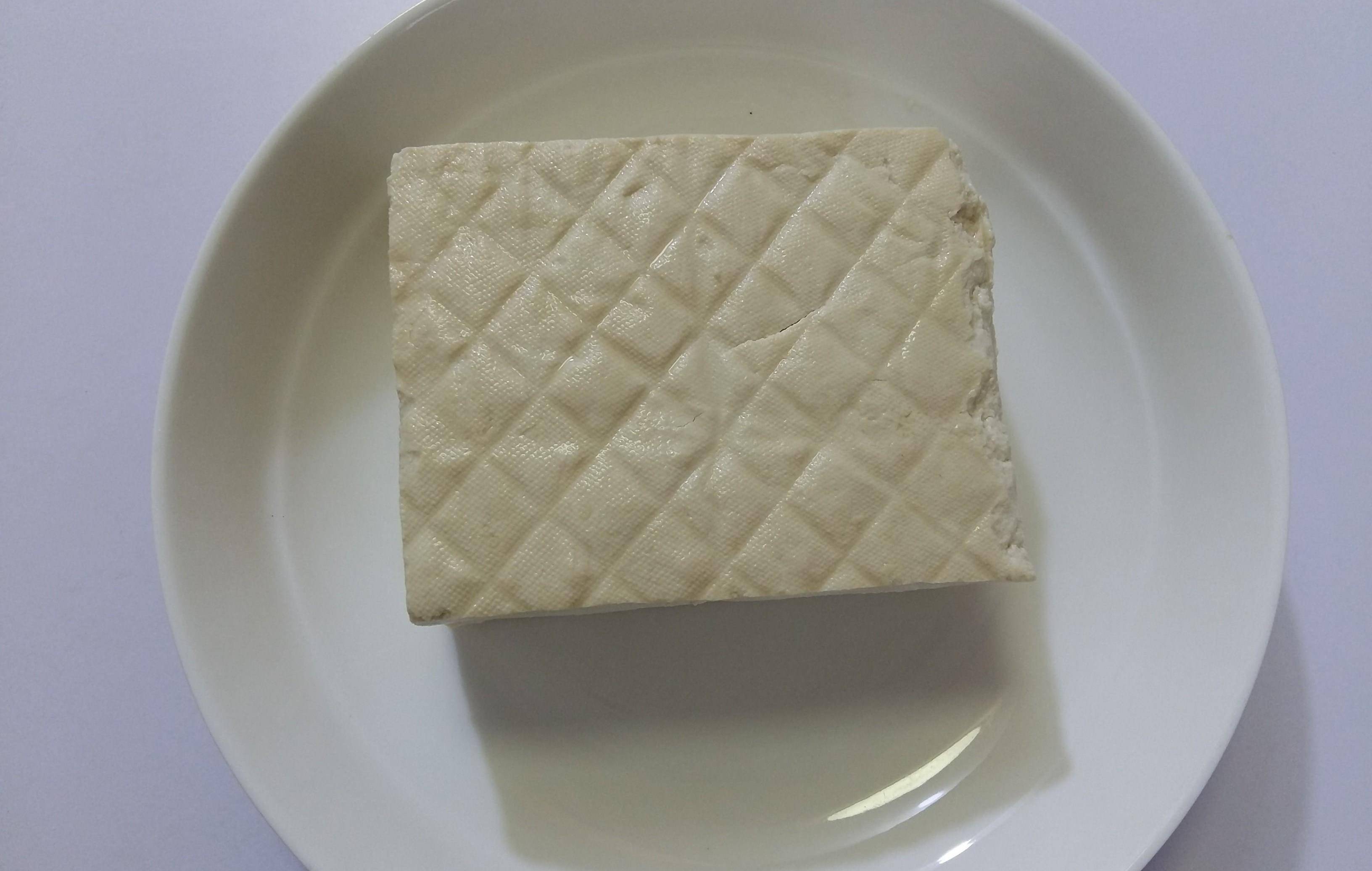 第二步:豆腐切成厚约8毫米的三角片,豆腐切三角不易碎;大蒜去皮拍扁剁