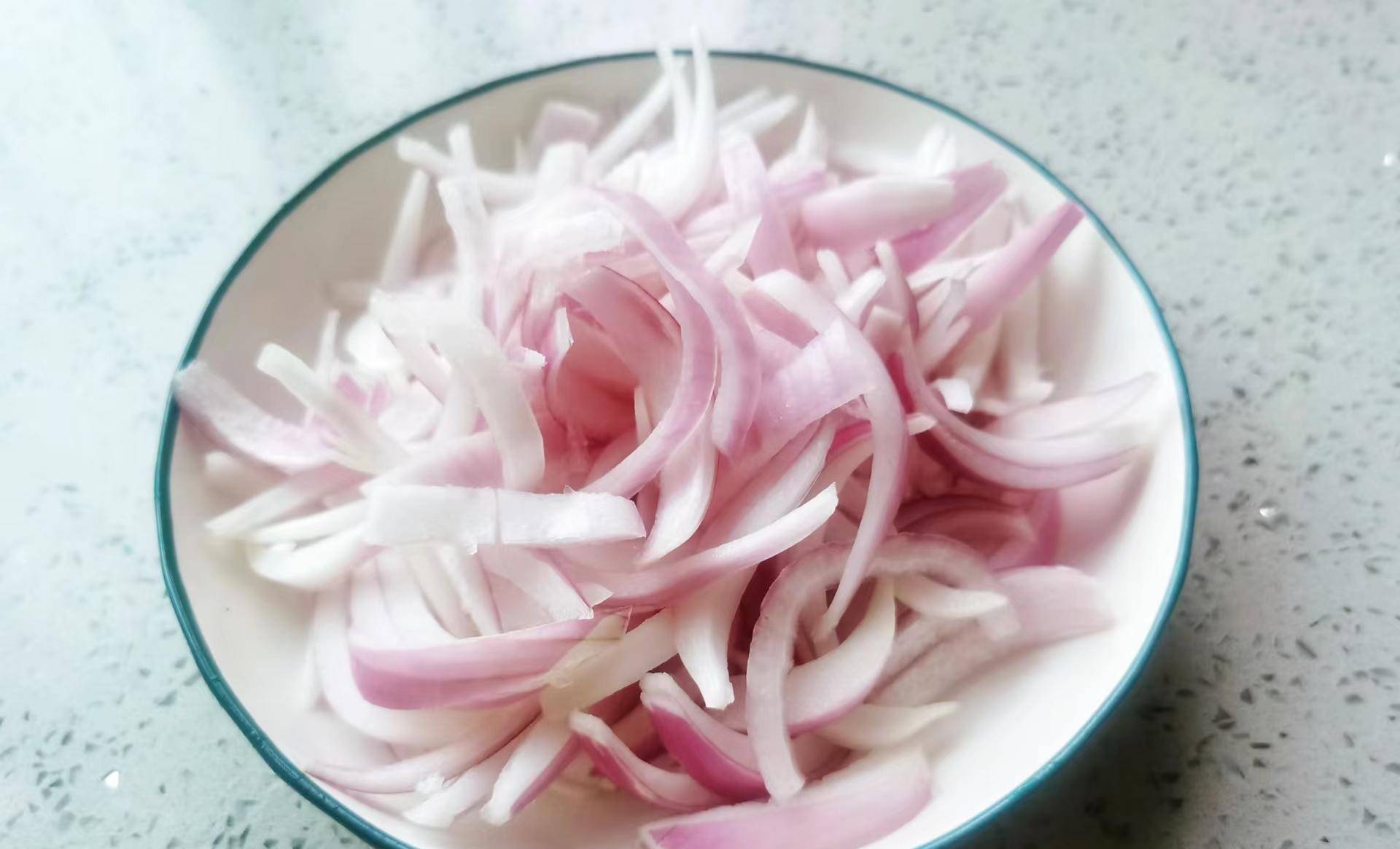 洋葱剥去外皮,接着去头去尾再改刀切成条,然后将切好的洋葱条清洗干净