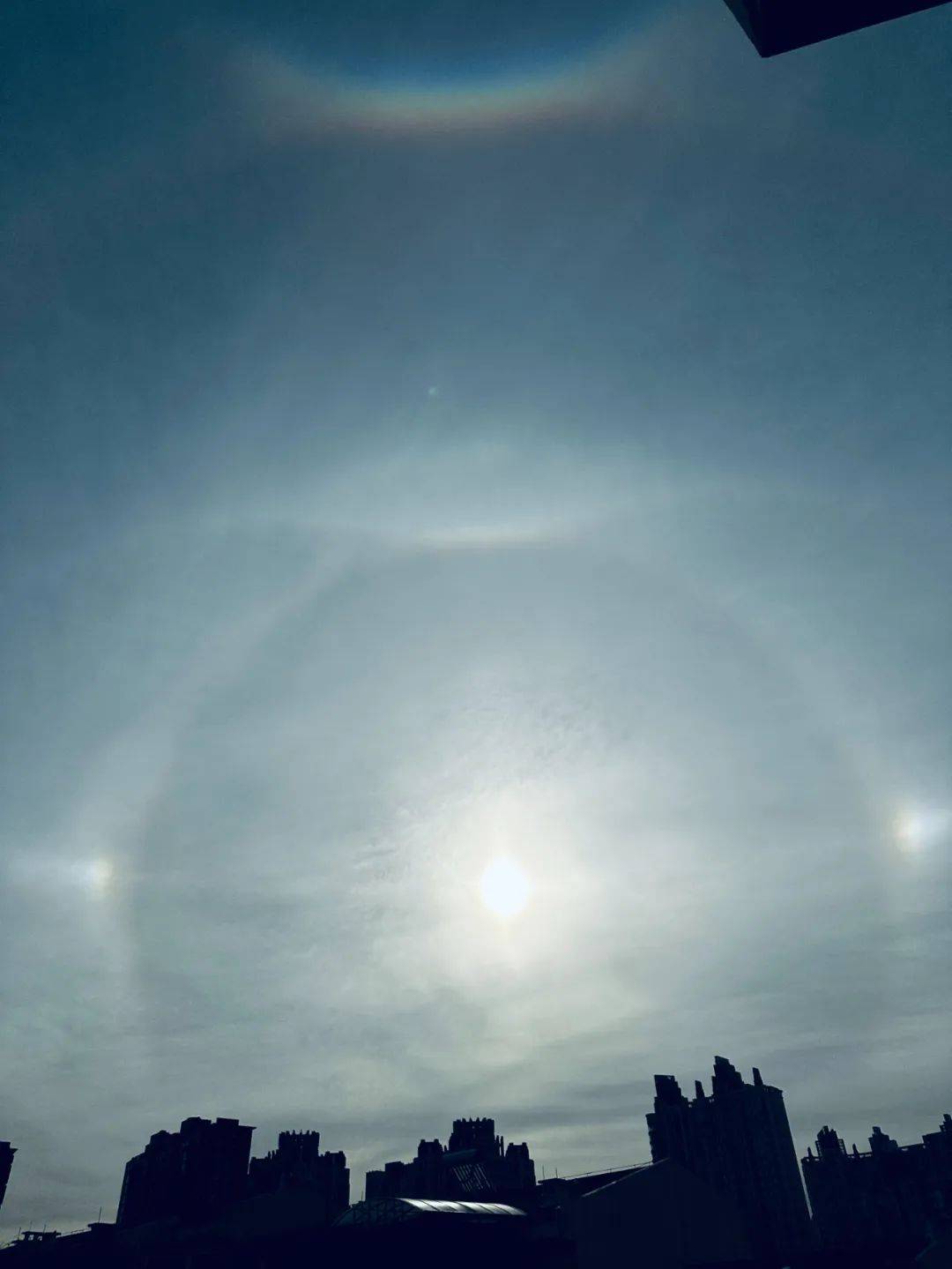 大光圈为日晕太阳左右两边是一对幻日大光圈最顶部彩虹色的微笑是