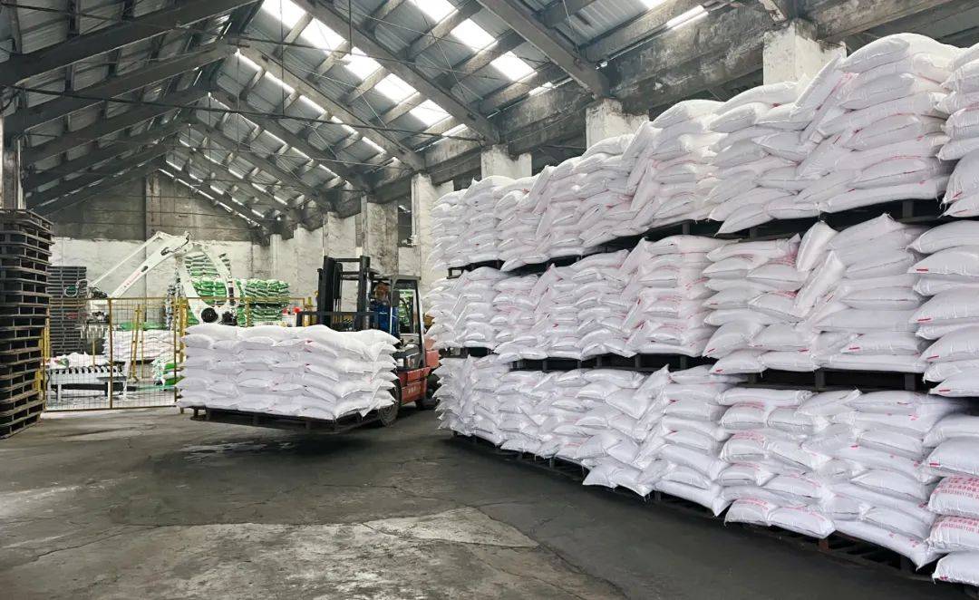 走进仓库,只见一包包化肥整齐堆满仓库,运输车辆你来我往,工人们正忙