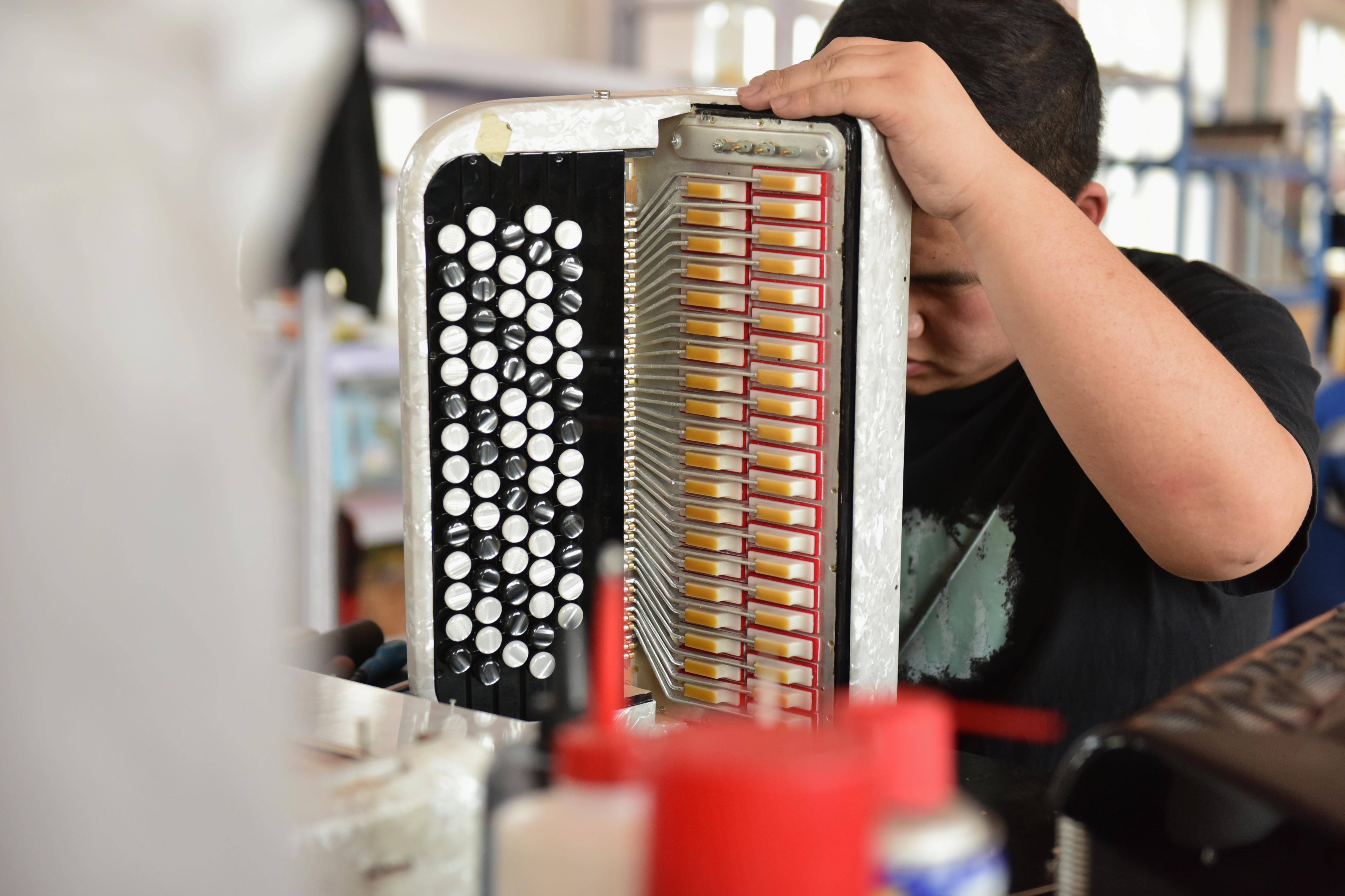 5月25日,在天津鹦鹉乐器有限公司,工人在检查一台键纽式手风琴.